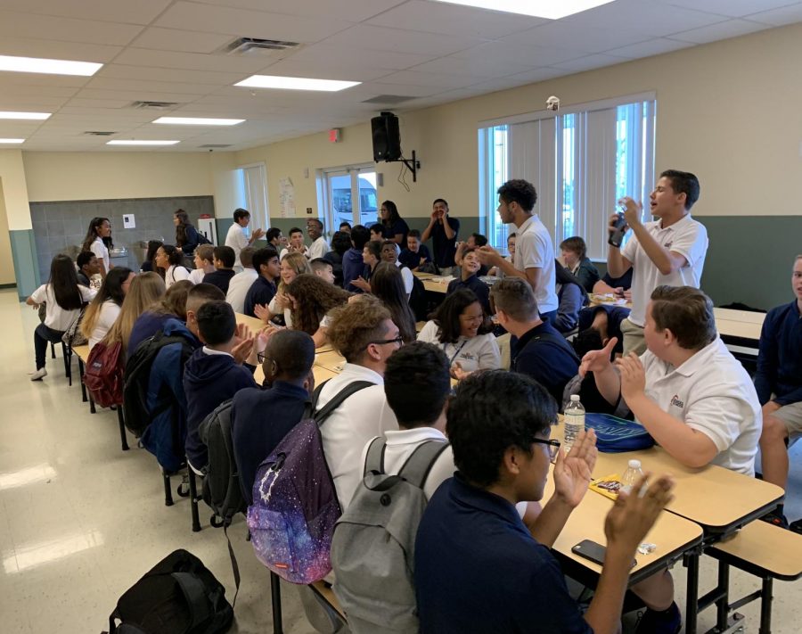 Students in the lunch room clap along while other students sing happy birthday. 