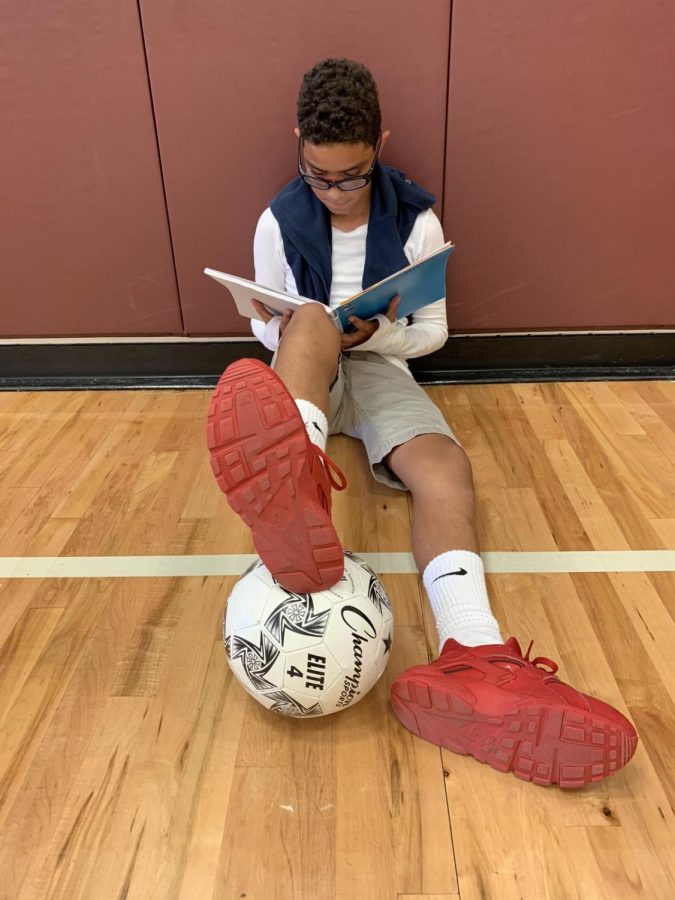  6th grader, Jedriel Perez, studying notes in the gym before he plays soccer.