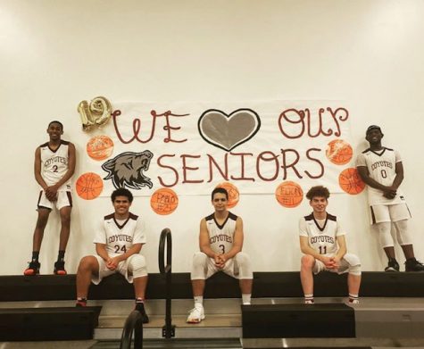 The senior basketball players pose for a picture next to the banner made by SGA.