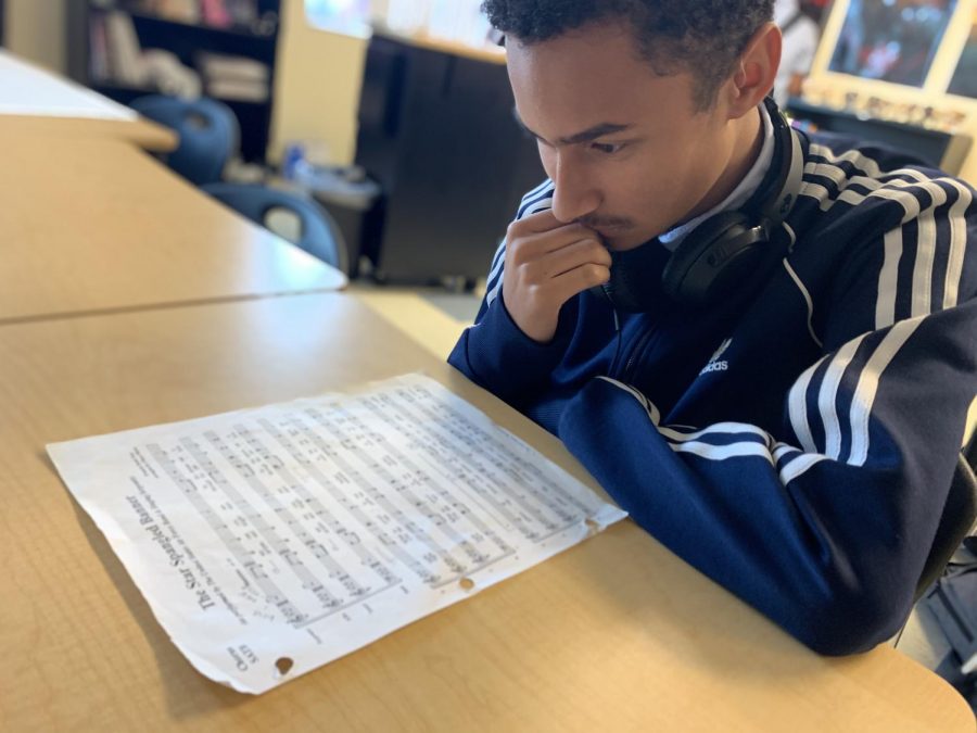 Senior Alex Paris looks over a sheet of music.