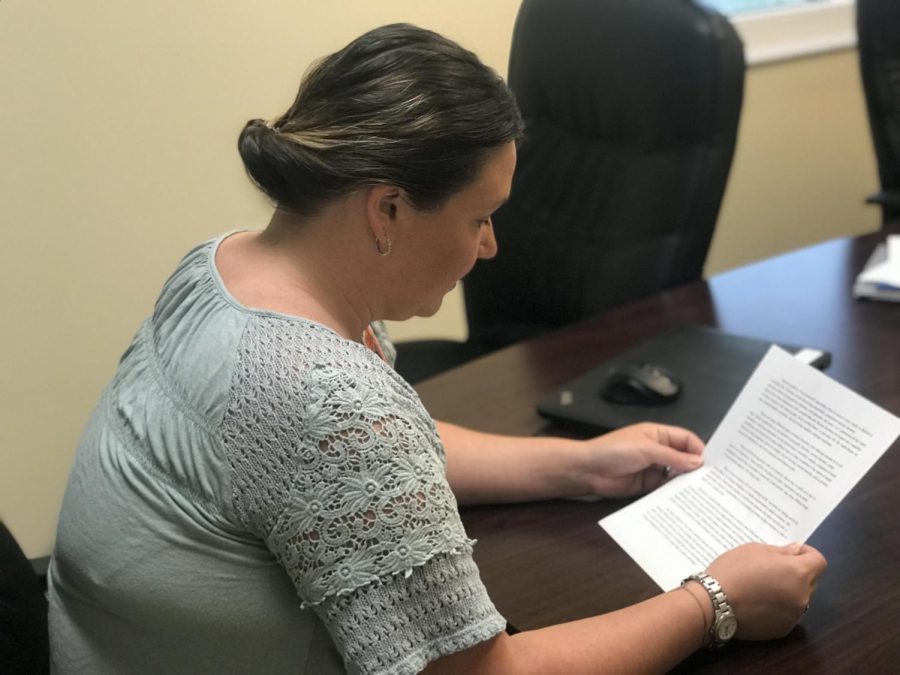 Ms. Sarah Berger, counselor, reading a document related to mental health.