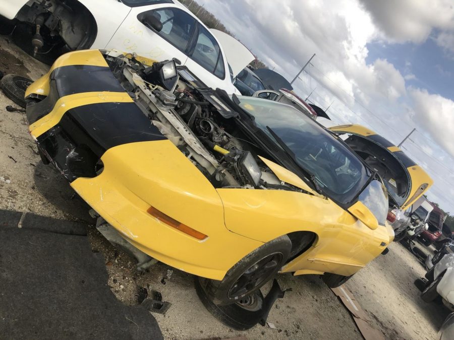 Car at junkyard with hood removed. 