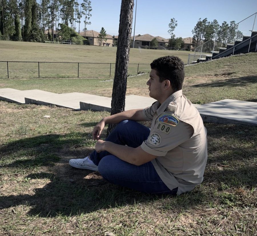 Luis Lugo sitting under a tree in his Boy Scouts Uniform