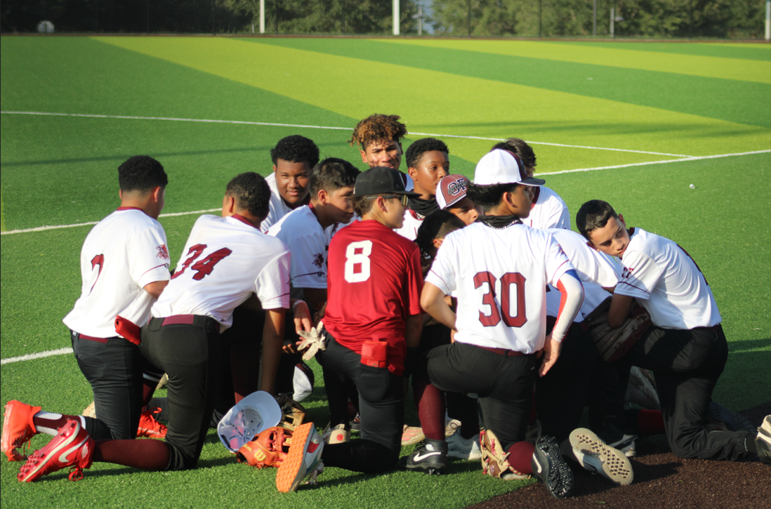 The baseball team gets down on their knees before the game for an inspirational speech. 