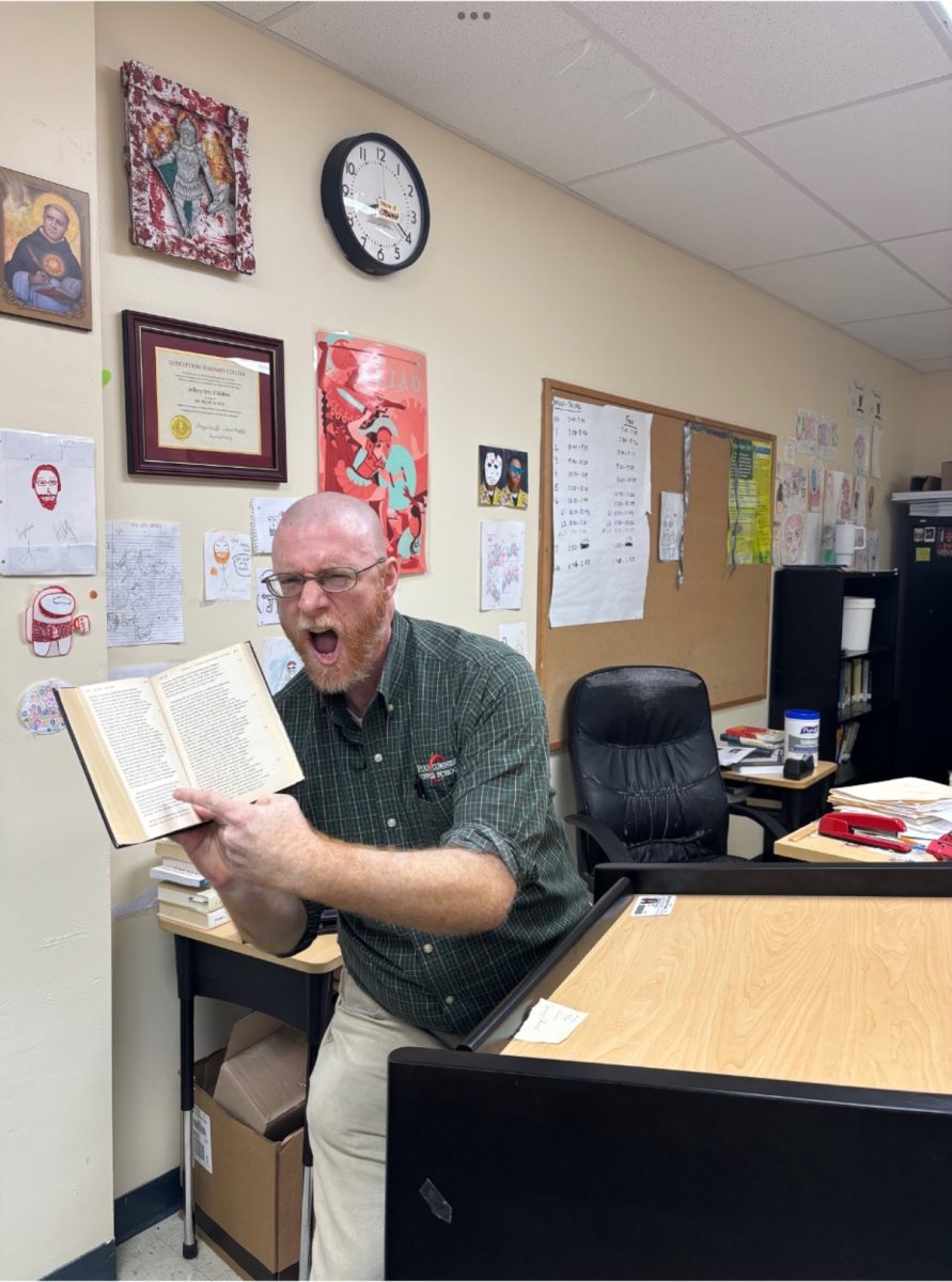 Mr. Childers enthusiastically points at a book in class.