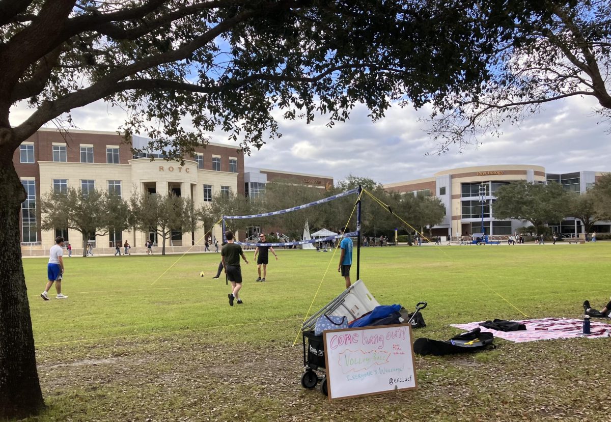 UCF students play volleyball in campus field.