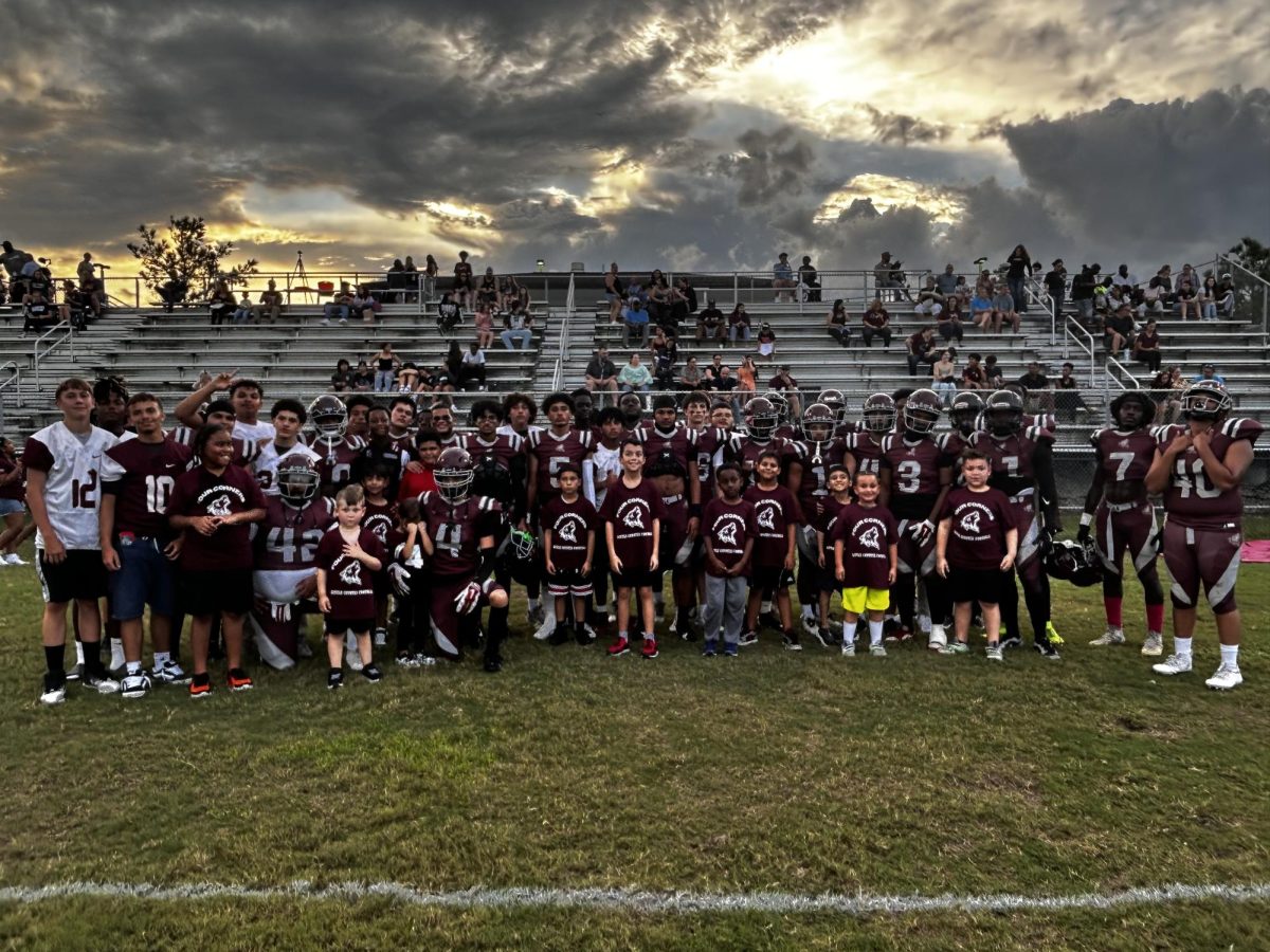 The football team and the students from the lower campus pose for a photo during the homecoming game.