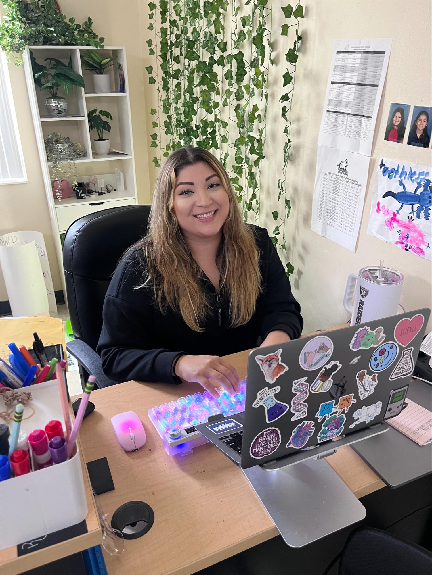 Diana Albitre smiles for a photo at her well decorated desk. 