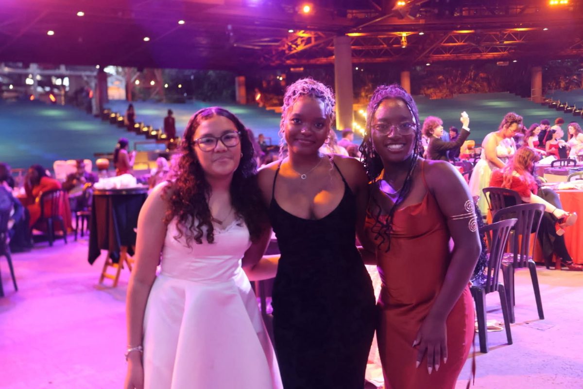 Daniely Gonzalez, Gabrielle Destine, and Sheniqua Jospeh smile for a photo at prom. 
