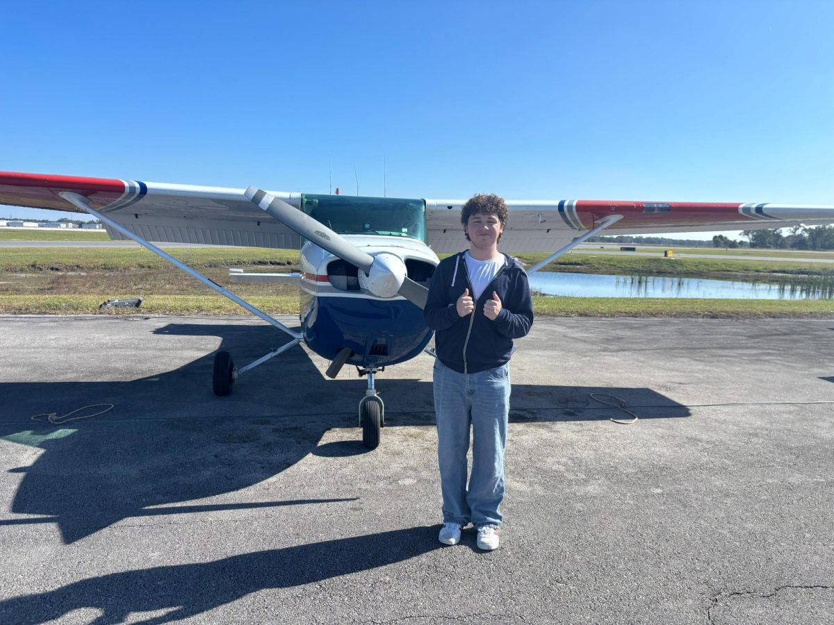Senior Reuben Young of Four Corners Upper School next to a Plane.